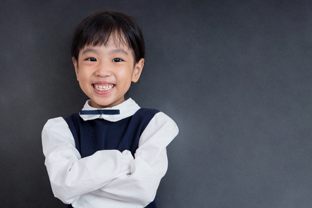 Asian Chinese little girl standing in front of blackboard in isolated black backgroundの写真素材