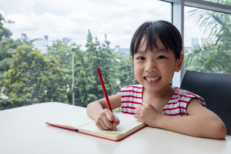 Asian little Chinese girl writing homework at homeの写真素材