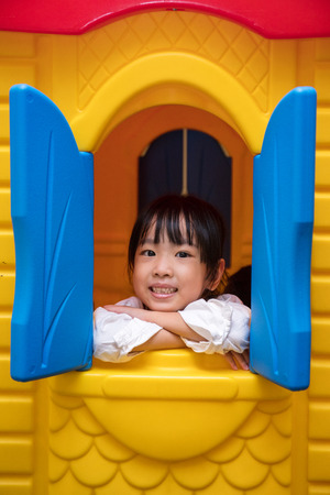 Asian Chinese little girl playing in toy house at indoor playgroundの写真素材