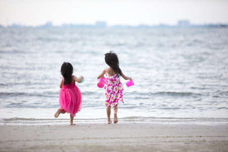Asian Chinese little sisters having fun at beach outdoorの写真素材