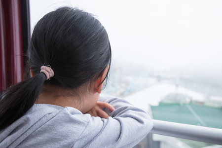 Asian chinese little girl riding cable car and enjoying the viewの写真素材