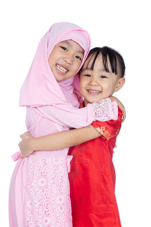 Asian Chinese little sisters wearing cheongsam and traditional Malay costume in isolated white backgroundの写真素材