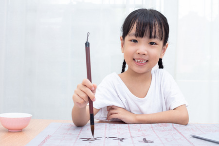 Asian little Chinese girl practice Chinese calligraphy at homeの写真素材