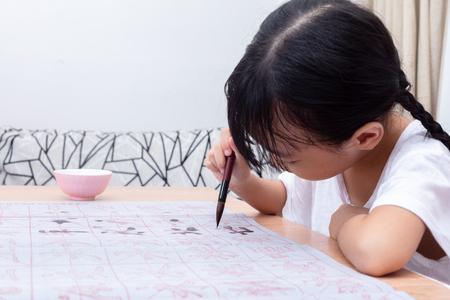 Asian little Chinese girl practice Chinese calligraphy at homeの写真素材