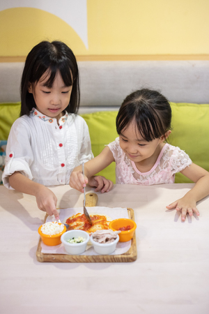 Asian Little Chinese Girls DIY mini pizza at homeの写真素材