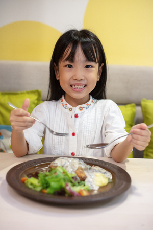 Asian Little Chinese Girl Eating Western Food at restaurantの写真素材
