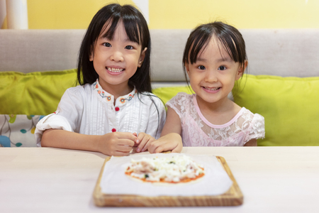 Asian Little Chinese Girls DIY mini pizza at homeの写真素材