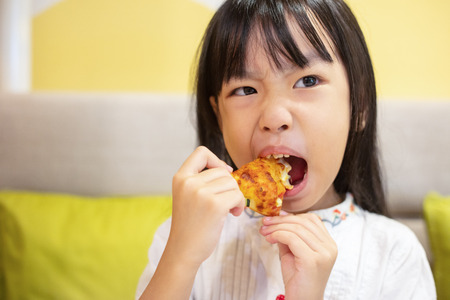 Asian Little Chinese Girl Eating pizza at restaurantの写真素材
