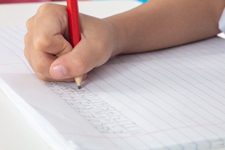 Children's hands holding pencil and doing homework at home