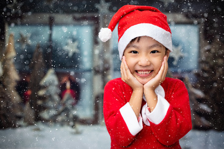 Asian Chinese little girl playing with snowflakes outdoor during christmas eveの写真素材