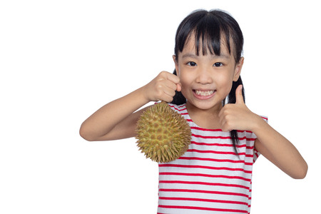 Asian Chinese little girl holding durian fruit with thumbs up in isolated white backgroundの写真素材