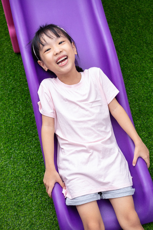 Asian Chinese Little Girl Playing on the slide at outdoor playgroundの写真素材