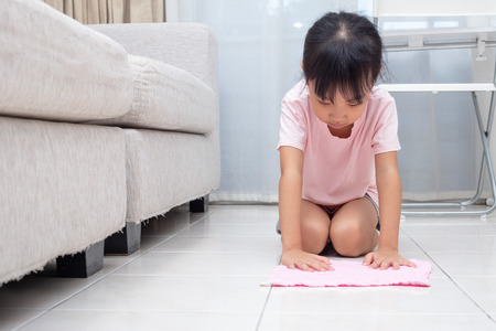 Asian Chinese little girl helping doing cleaning with rag at homeの写真素材