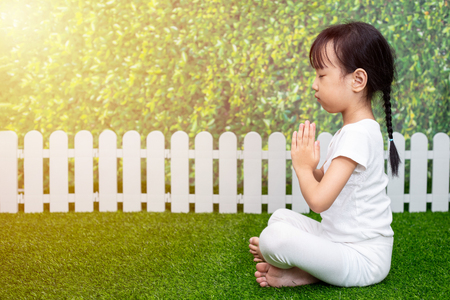 Asian Chinese little girl practicing yoga pose on a mat outdoorの写真素材