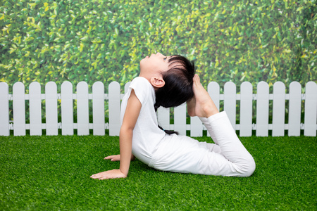 Asian Chinese little girl practicing yoga pose on a mat outdoorの写真素材
