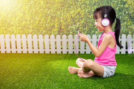 Asian Little Chinese girl playing with mobile phone at outdoor parkの写真素材