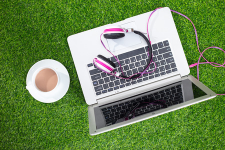 Headphones on the laptop on grass at outdoor parkの写真素材
