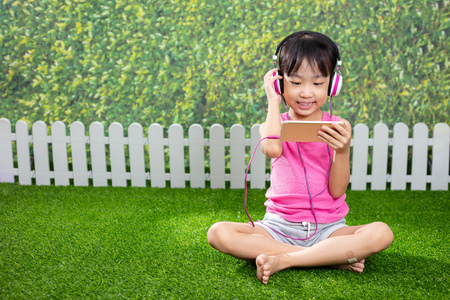 Asian Little Chinese girl playing with mobile phone at outdoor parkの写真素材