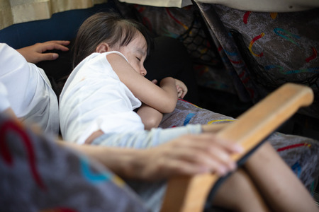 Asian Chinese little girl sleeping on mother's legs on the busの写真素材
