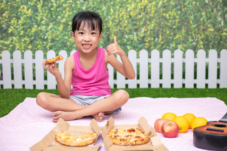 Asian Chinese little girl Eating Pizza at outdoor gardenの写真素材