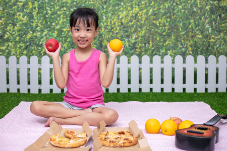 Asian Chinese little girl having picnic at outdoor gardenの写真素材