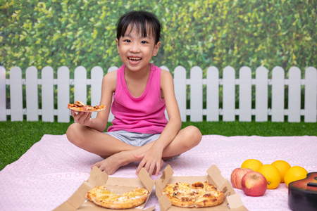 Asian Chinese little girl Eating Pizza at outdoor gardenの写真素材