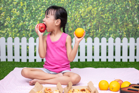 Asian Chinese little girl having picnic at outdoor gardenの写真素材