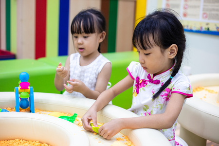Asian Chinese Little Sisters Playing Kinetic Sand At Indoor Playgroundの写真素材