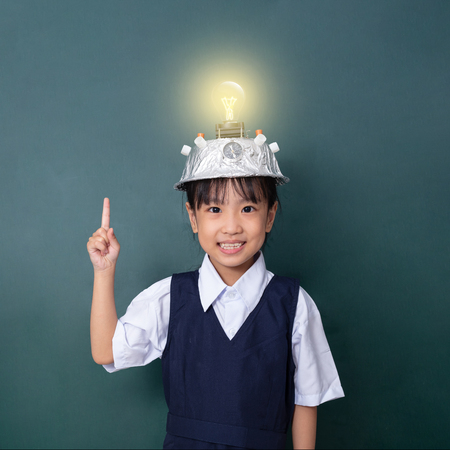 Asian chinese little girl wearing virtual reality helmet and pointing finger up to light bulb...