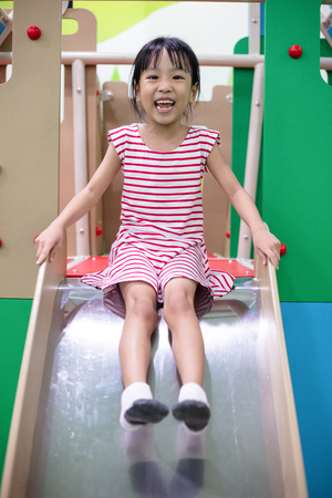 Asian Chinese little girl playing on the slide at indoor playgroundの写真素材