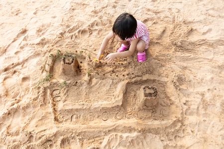 Asian Chinese little girl playing sand at beach outdoorの写真素材