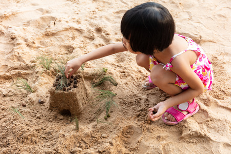Asian Chinese little girl playing sand at beach outdoorの写真素材