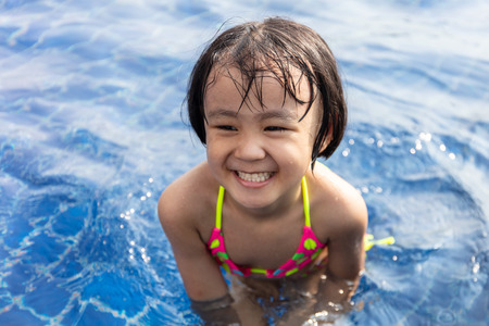 Asian Little Chinese Girl Playing in Swimming Pool Outdoorの写真素材