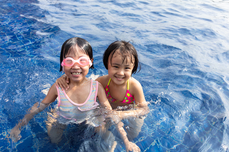 Asian Little Chinese Sisters Playing in Swimming Pool Outdoorの写真素材