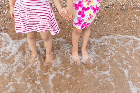 Asian Chinese little sisters playing water at beach outdoorの写真素材