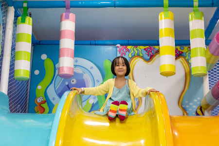 Asian Chinese little girl playing on the slide at indoor playgroundの写真素材