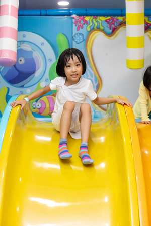 Asian Chinese little girl playing on the slide at indoor playgroundの写真素材