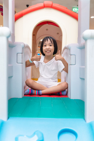 Asian Chinese little girl playing in toy house at indoor playgroundの写真素材