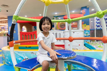 Asian Chinese little girl sitting in the carousel at indoor playgroundの写真素材