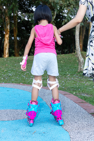 Asian Chinese little girl playing with roller skates at outdoor playgroundの写真素材