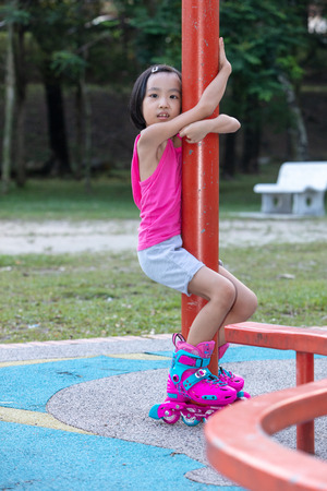 Asian Chinese little girl playing with roller skates at outdoor playgroundの写真素材