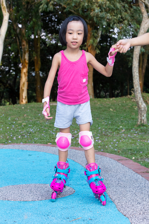 Asian Chinese little girl playing with roller skates at outdoor playgroundの写真素材