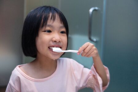 Asian Little Chinese Girl brushing her teeth in the restroom