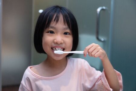 Asian Little Chinese Girl brushing her teeth in the restroomの写真素材