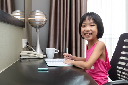 Asian Little Chinese Girl doing homework at homeの写真素材