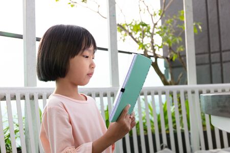 Asian Little Chinese Girl reading book in the outdoor cafeの写真素材