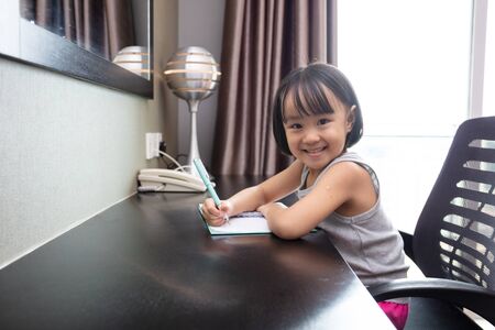 Asian Little Chinese Girl doing homework at homeの写真素材