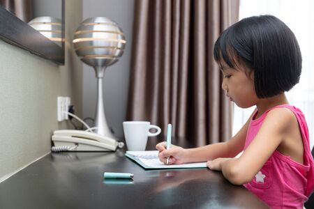 Asian Little Chinese Girl doing homework at homeの写真素材