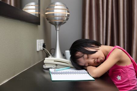 Asian Little Chinese Girl falling alseep while doing homework at homeの写真素材