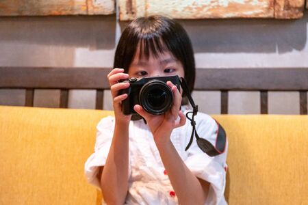Asian Little Chinese Girl playing camera at an indoor cafeの写真素材